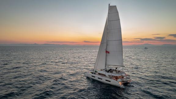 Der Katamaran White Caps segelt bei ruhigem Sonnenuntergang.