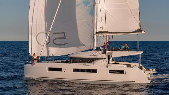 A luxurious Lagoon 50 sailing at sunset, with people enjoying the view and relaxing on deck.