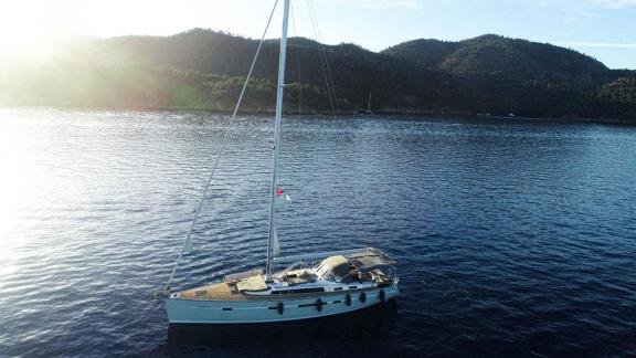 The sailing yacht Özgürüm is anchored in a peaceful bay surrounded by Göcek's natural beauty.