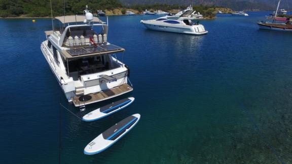 Motoryacht Ayşe Sultan 1 in einer Bucht vor Anker, mit Paddleboards und anderen Yachten in der Umgebung.