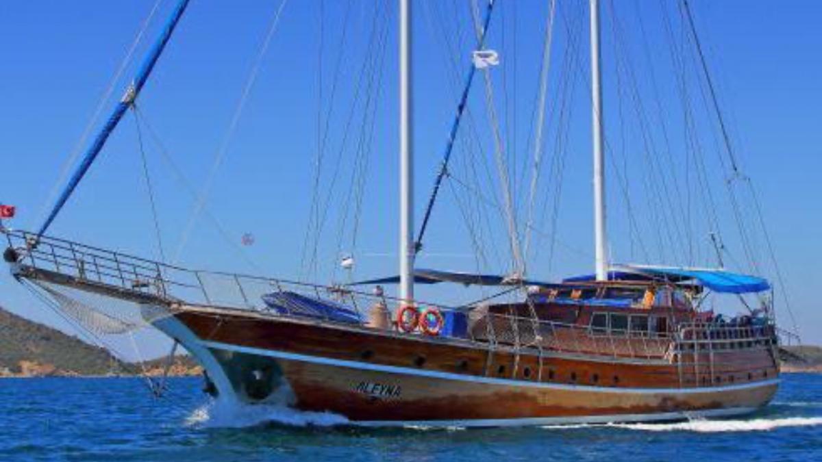 In the blue waters of Fethiye, a four-cabin wooden gulet is underway during the day.