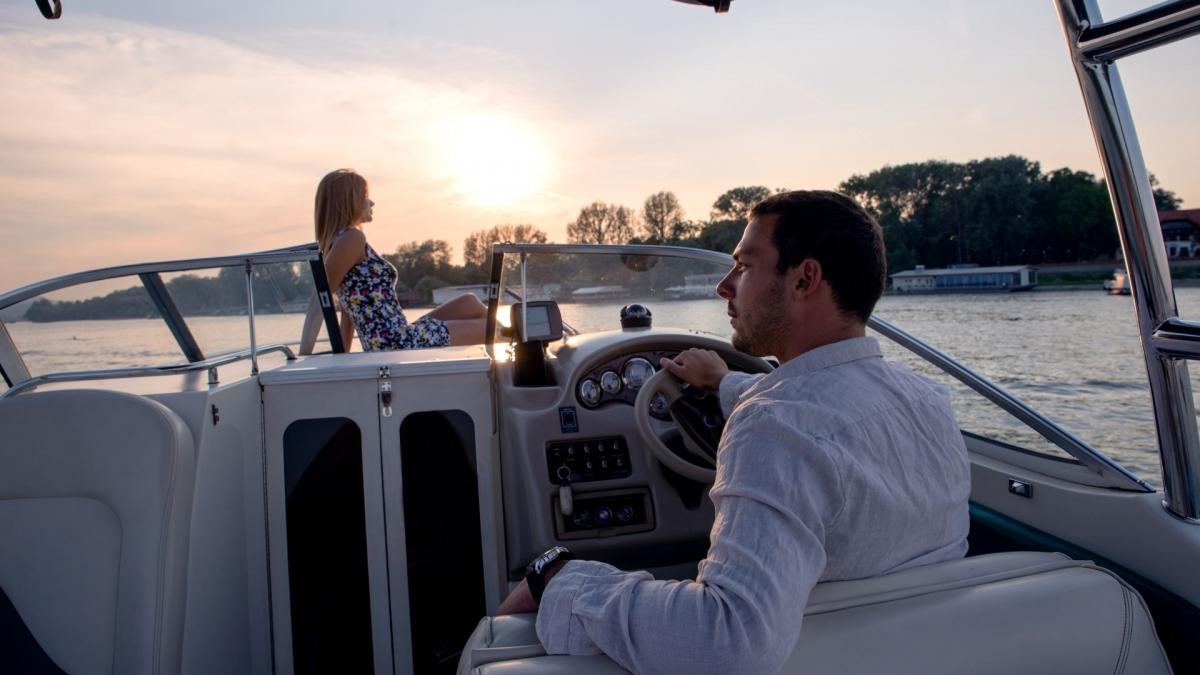 On a boat journey, a man in a white shirt drives the boat while his wife watches the scenery.