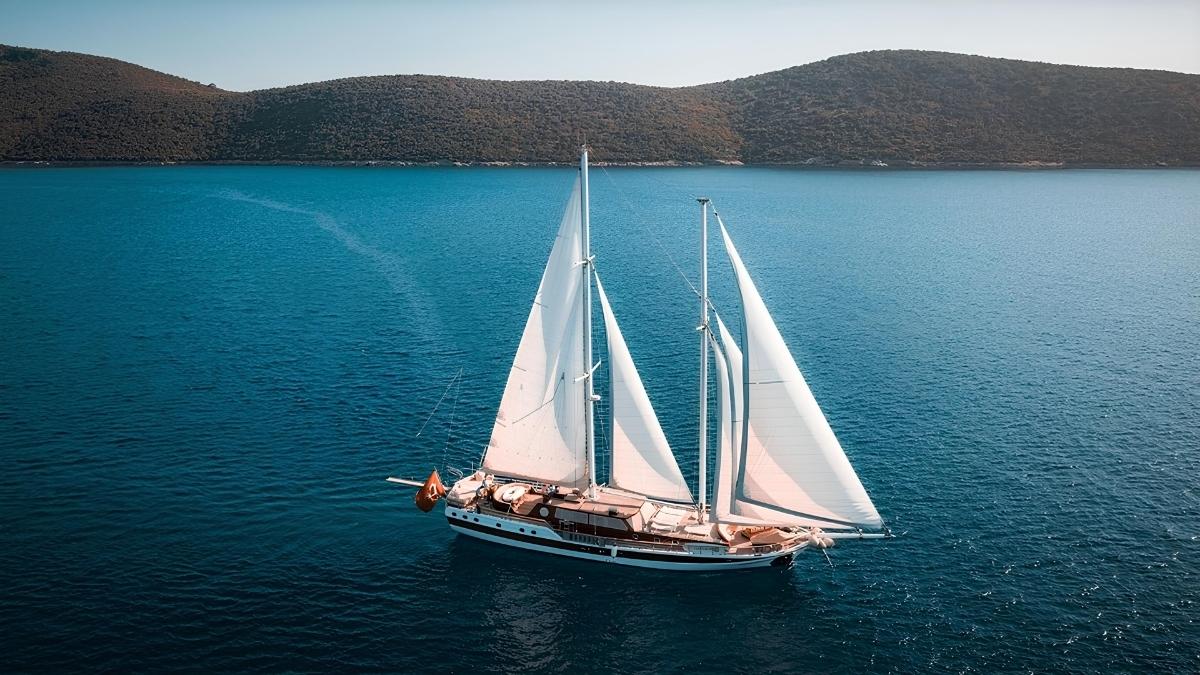 Elegant sailing yacht with white sails gliding along the picturesque coast of the Adriatic.