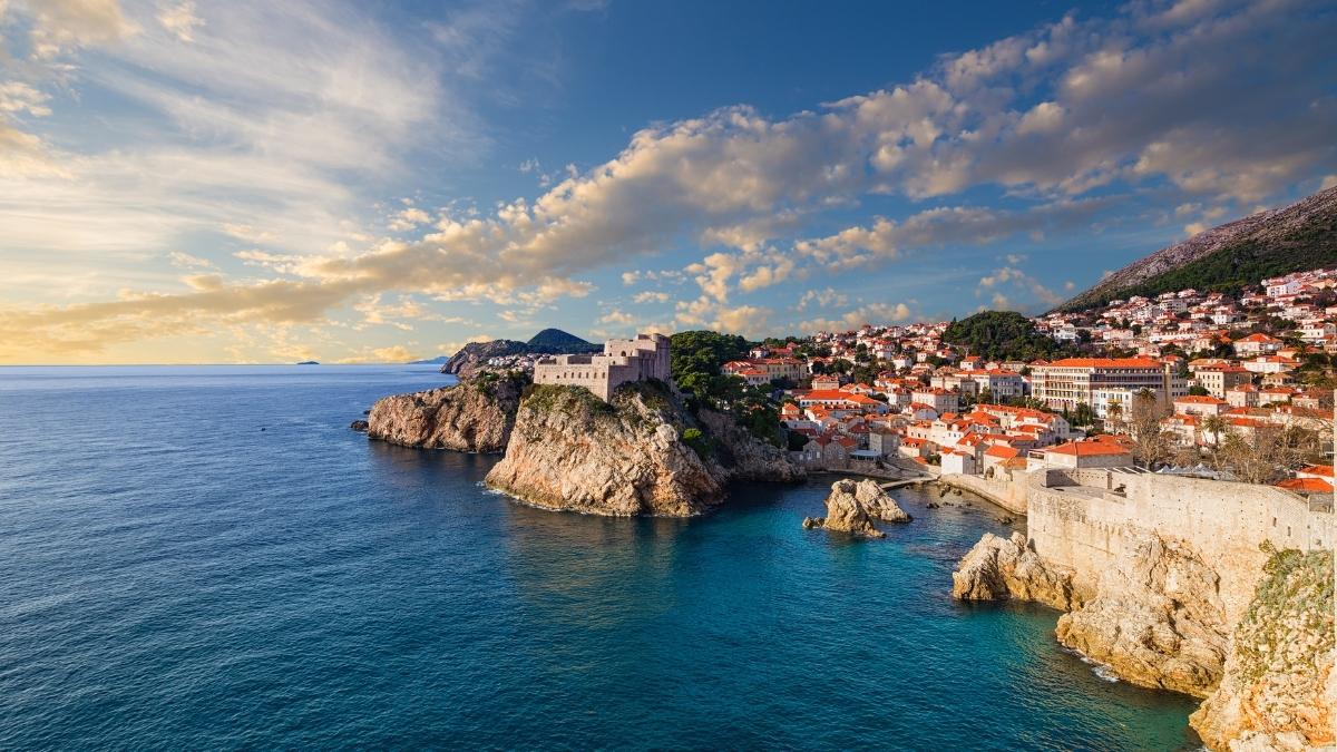 A stunning coastal town with red rooftops and a historic fort bathed in the warm light of the sunset