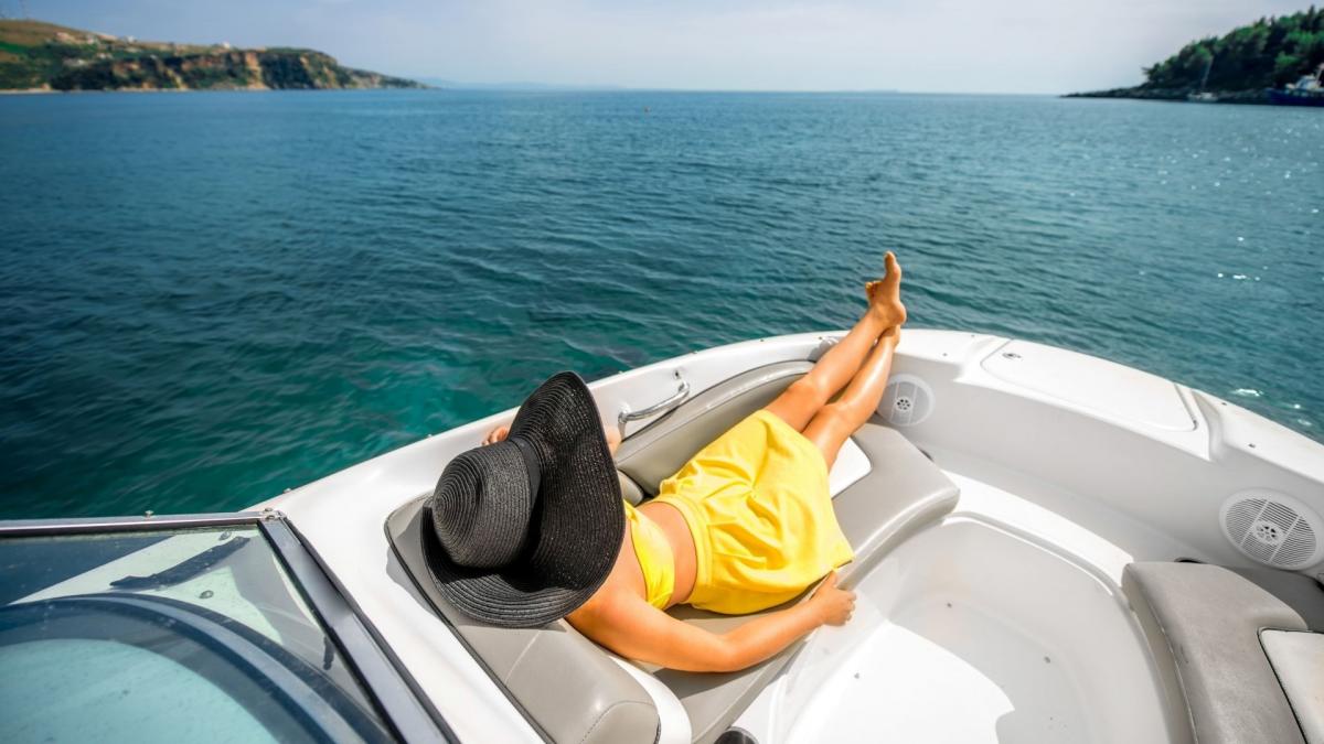 Eine Frau in einem gelben Badeanzug liegt allein und sonnt sich auf einer Luxusyacht.