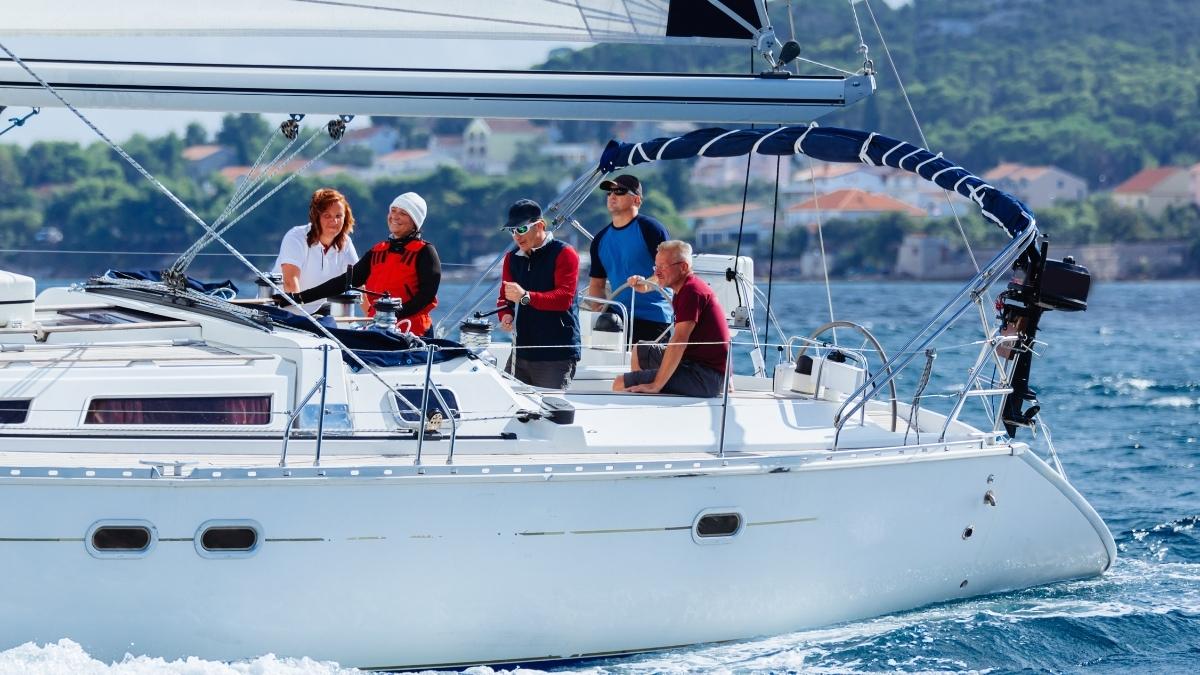 Gruppe von Freunden auf einer Yacht, die Sonne und Meer bei einer entspannten Segeltour genießen.