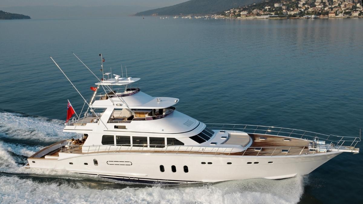 Eine elegante Motoryacht gleitet schnell über das ruhige Wasser, mit Küste im Hintergrund