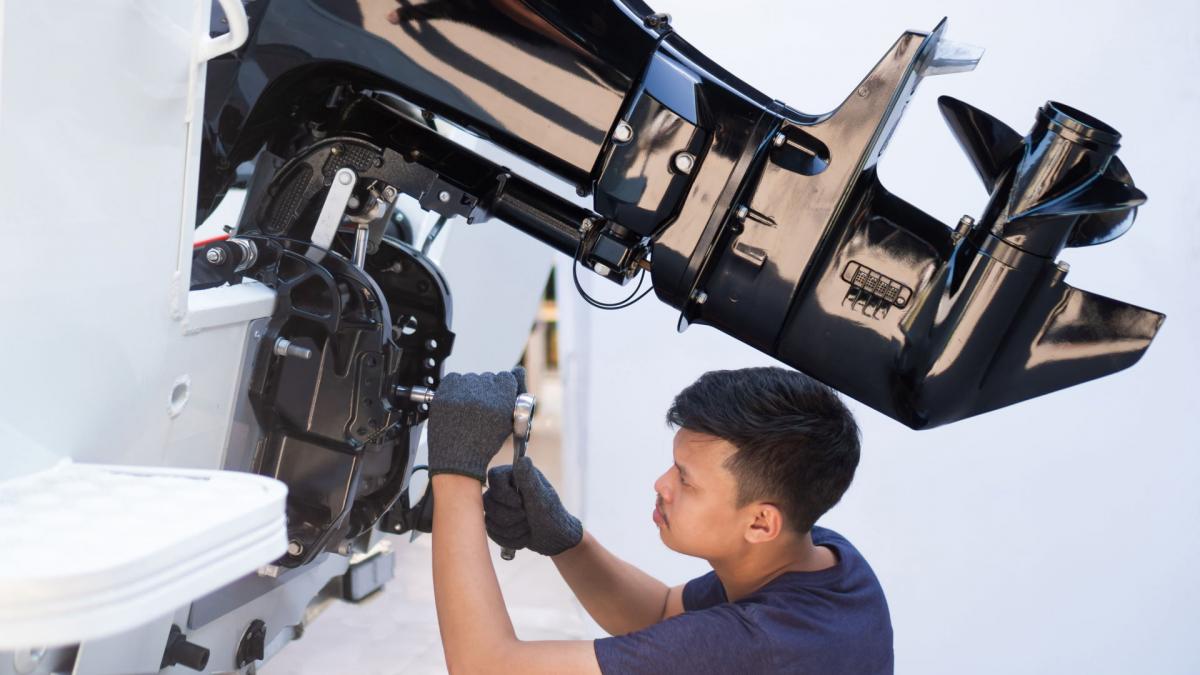 Ein Techniker zieht arbeite an einem Bootsmotor und zieht die letzte Schraube an.