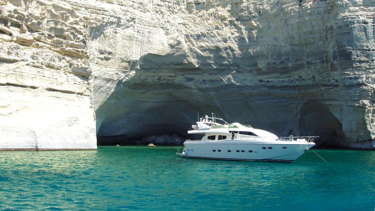 Eine luxuriöse Motoryacht ankert im türkisblauen Wasser vor beeindruckenden Felsformationen.