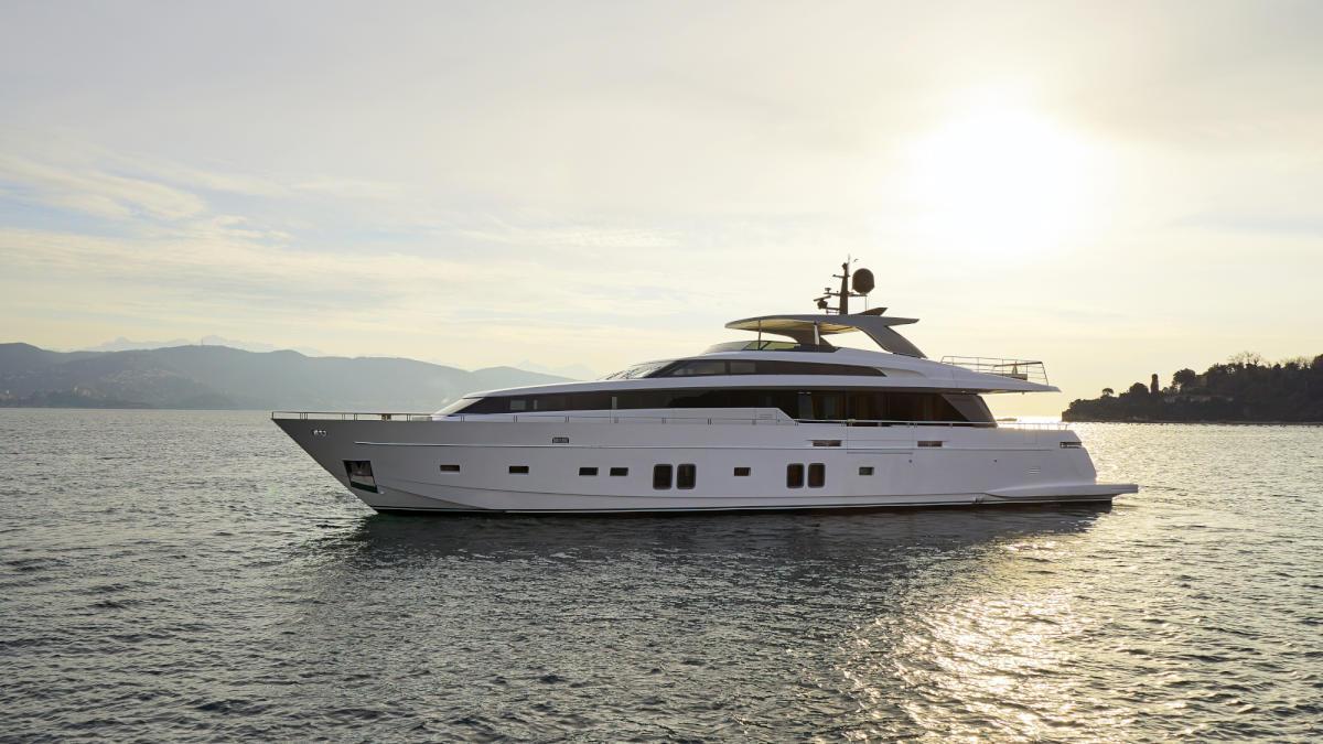 A modern motor yacht gently gliding through the water, illuminated by a golden sunset