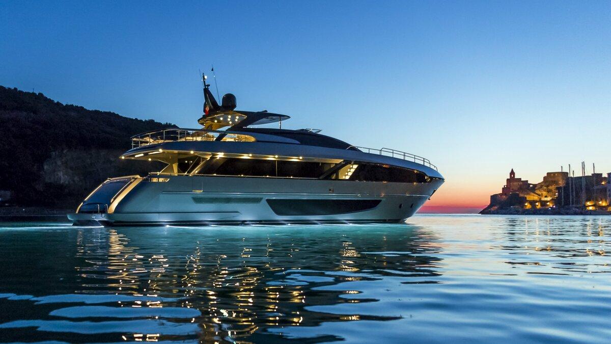 A mega yacht lies at anchor in a bay in the evening