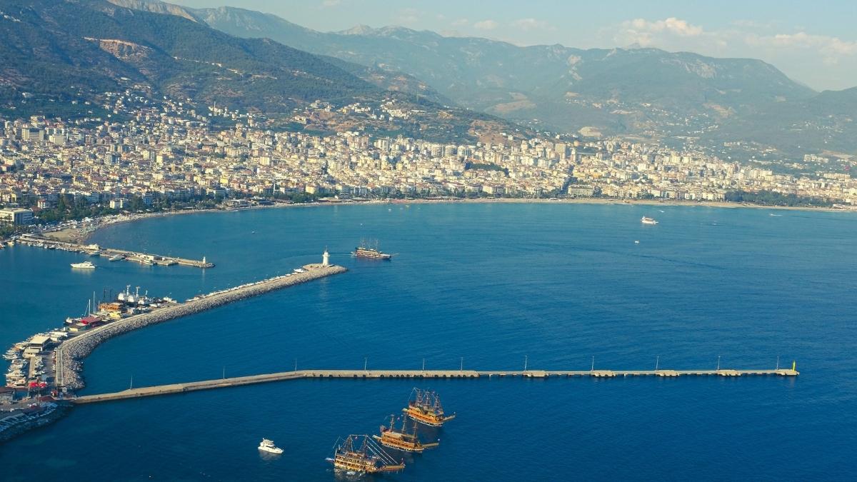 Luftaufnahme einer malerischen Küstenstadt in der Türkei mit einem langen Pier und Yachten im Hafen