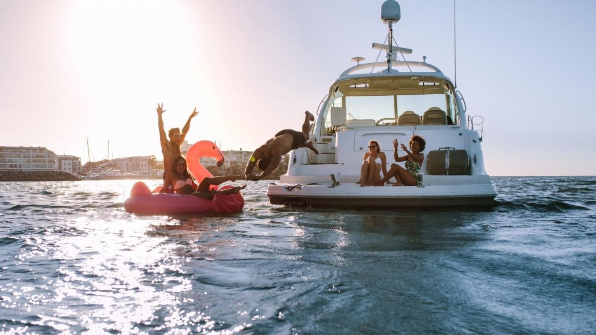 Eine Gruppe von Menschen, die gemeinsam Spaß haben, indem sie von einer Yacht ins Meer springen.