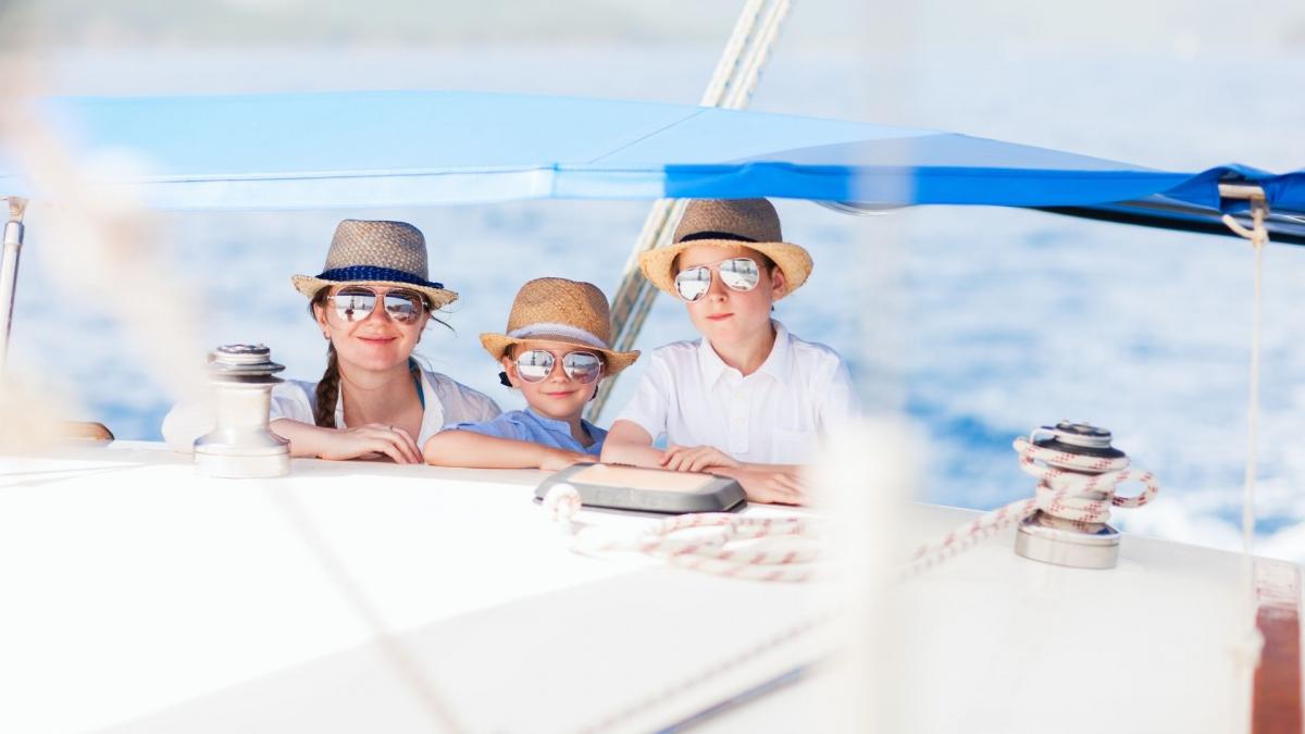 Eine Mutter, die auf einer Yacht Urlaub macht, fährt mit ihren beiden Kindern an Deck.
