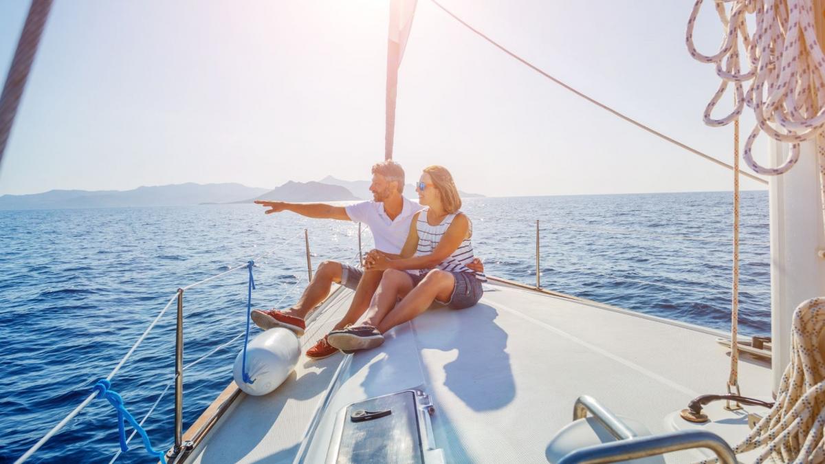 A couple relaxes on a life boat, enjoying the ocean view and sunny day