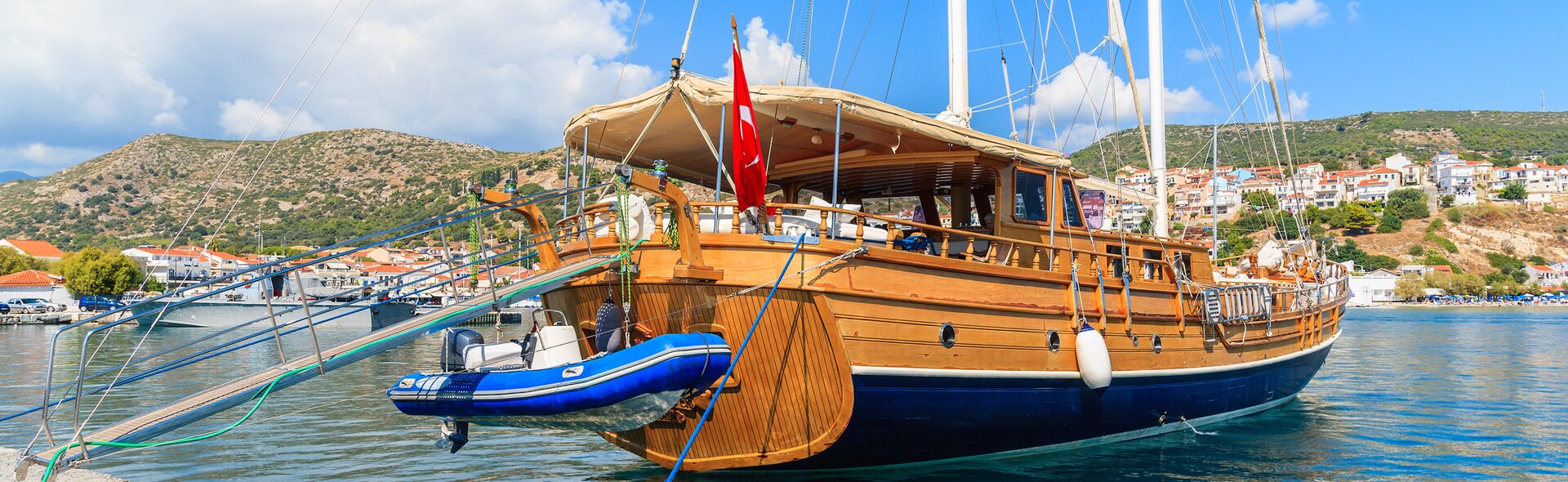 Eine traditionelle Holzgulet liegt für eine Blaue Reise Türkei am Kai vor einer malerischen Küstenstadt