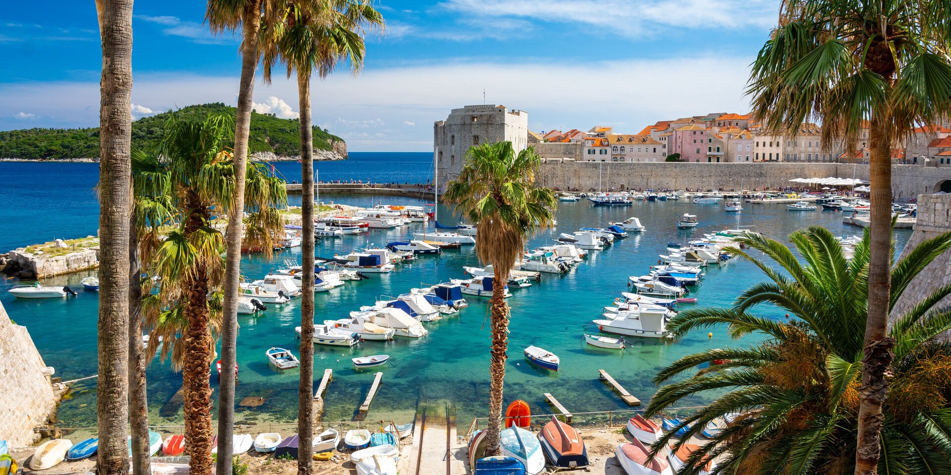 Многочисленные лодки в бирюзовых водах у стен Старого города, идеальная отправная точка для вашего проката лодок в Дубро