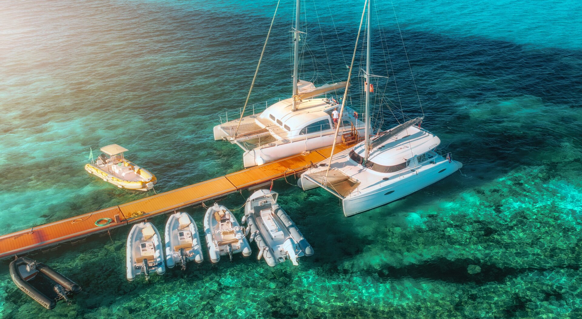 Zwei Luxuskatamarane und Beiboote am Dock während einer Katamaran-Tour Ibiza im goldenen Abendlicht