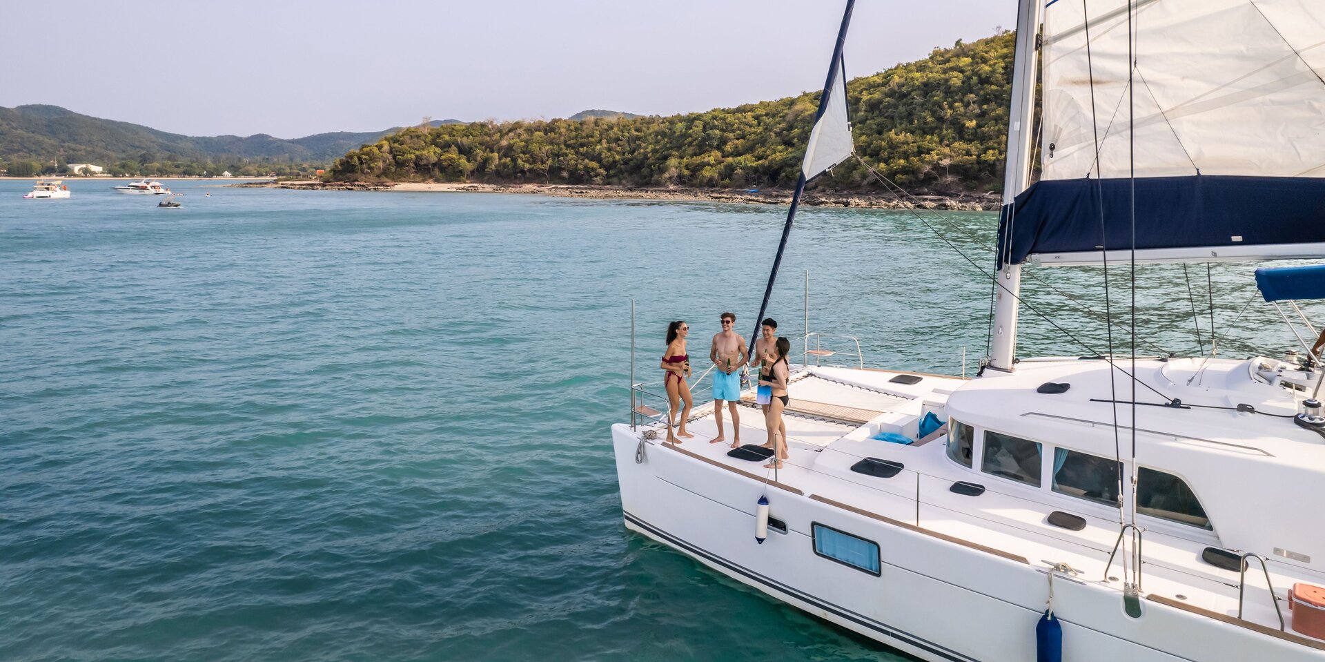 Glückliche Gruppe auf dem Deck, die einen Katamaran mieten in Lavrion, um gemeinsam die Küste zu befahren