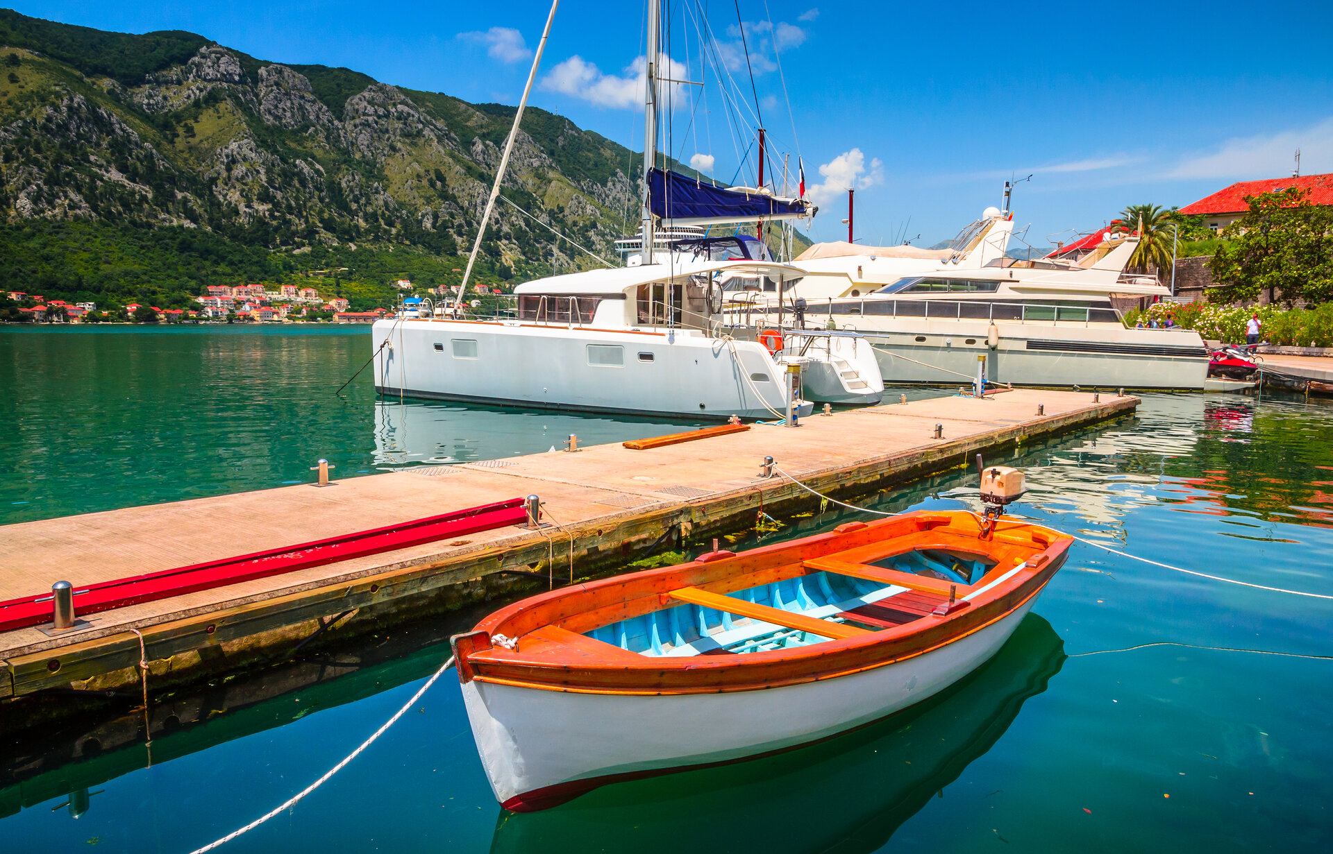 Ein exklusiver Katamaran liegt am Steg im Hafen von Kotor, Montenegro, vor der historischen Kulisse der Altstadt