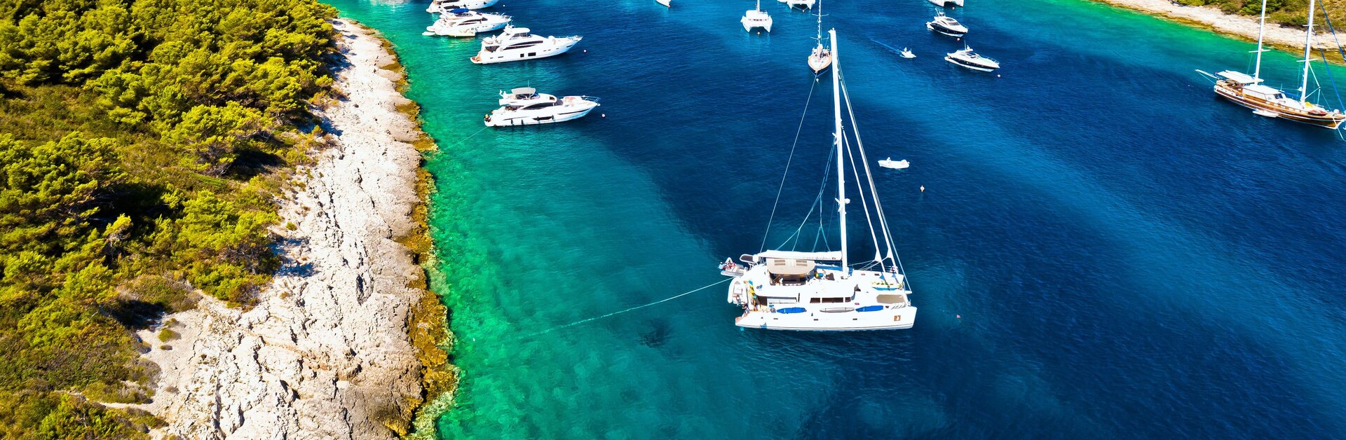 Gäste genießen ihren Katamaran Charter in Rogoznica beim Ankern im türkisfarbenen Wasser