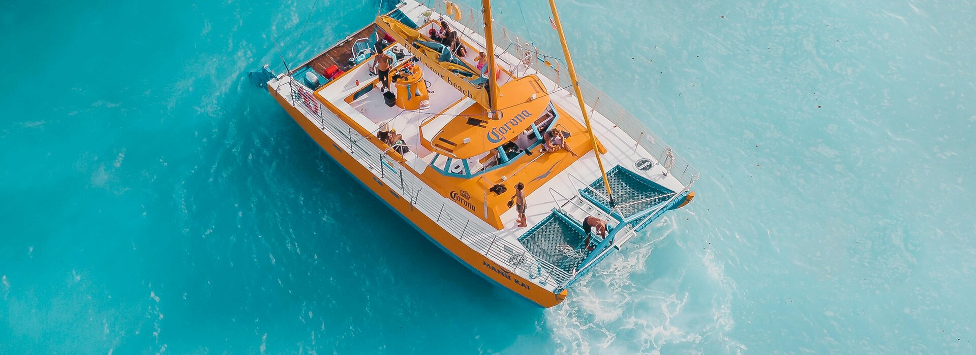 Turkuaz denizde güvertesinde yolcular olan sarı yelkenli katamaran, Olbia katamaran kiralama için harika bir an