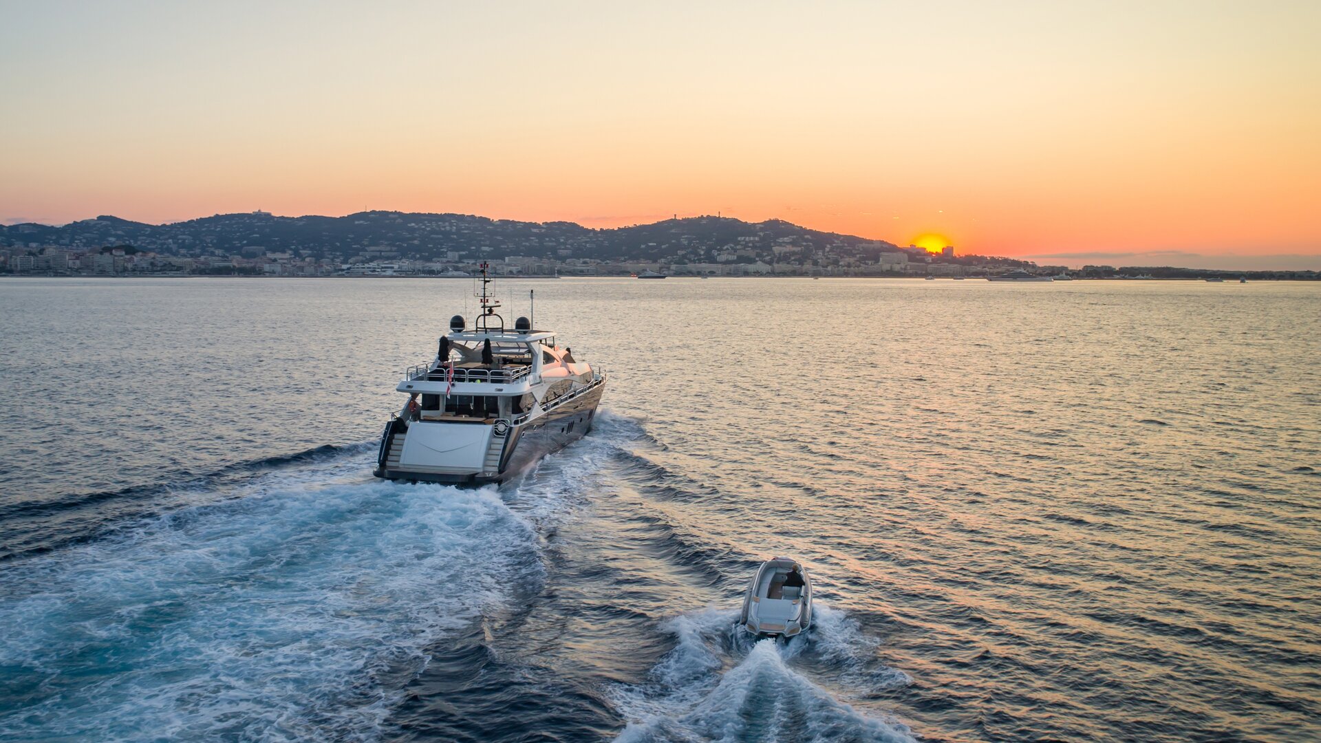 Stern view of a luxury motor yacht charter sailing at sunset