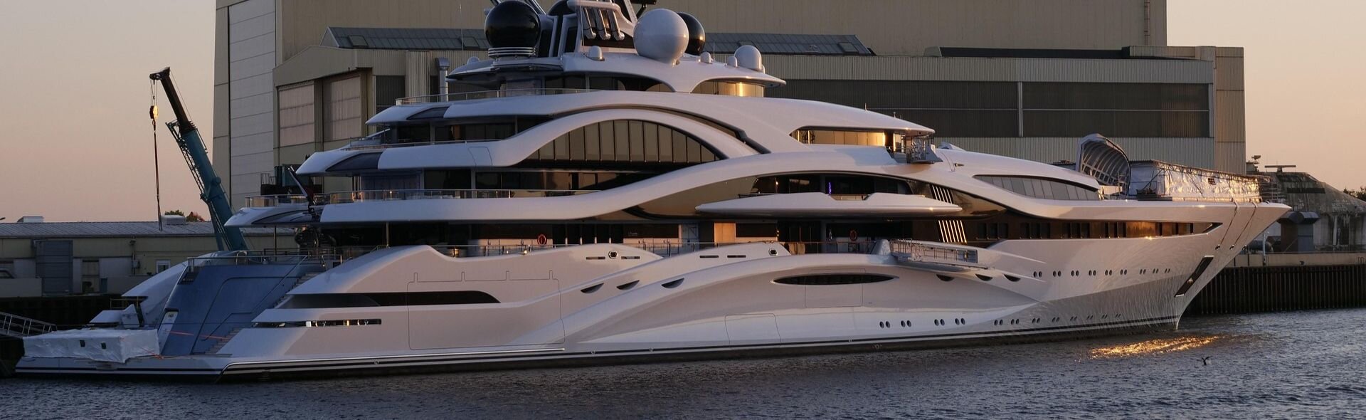 Вид сбоку на мега-яхту для аренды люксовой яхты в порту