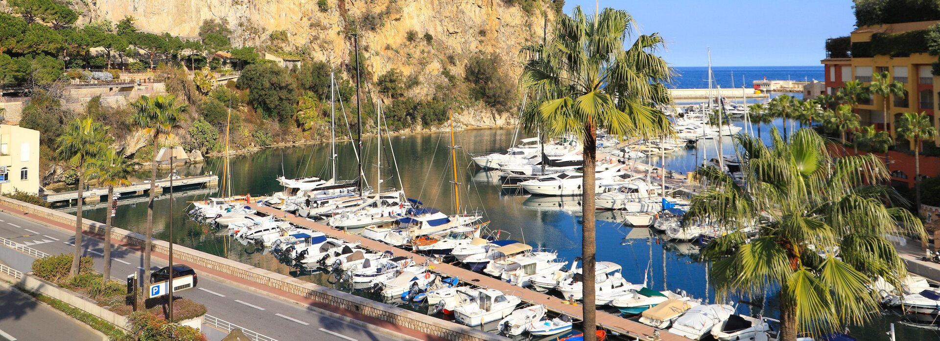View of Port de Fontvieille in Monaco with white yachts moored below steep cliffs