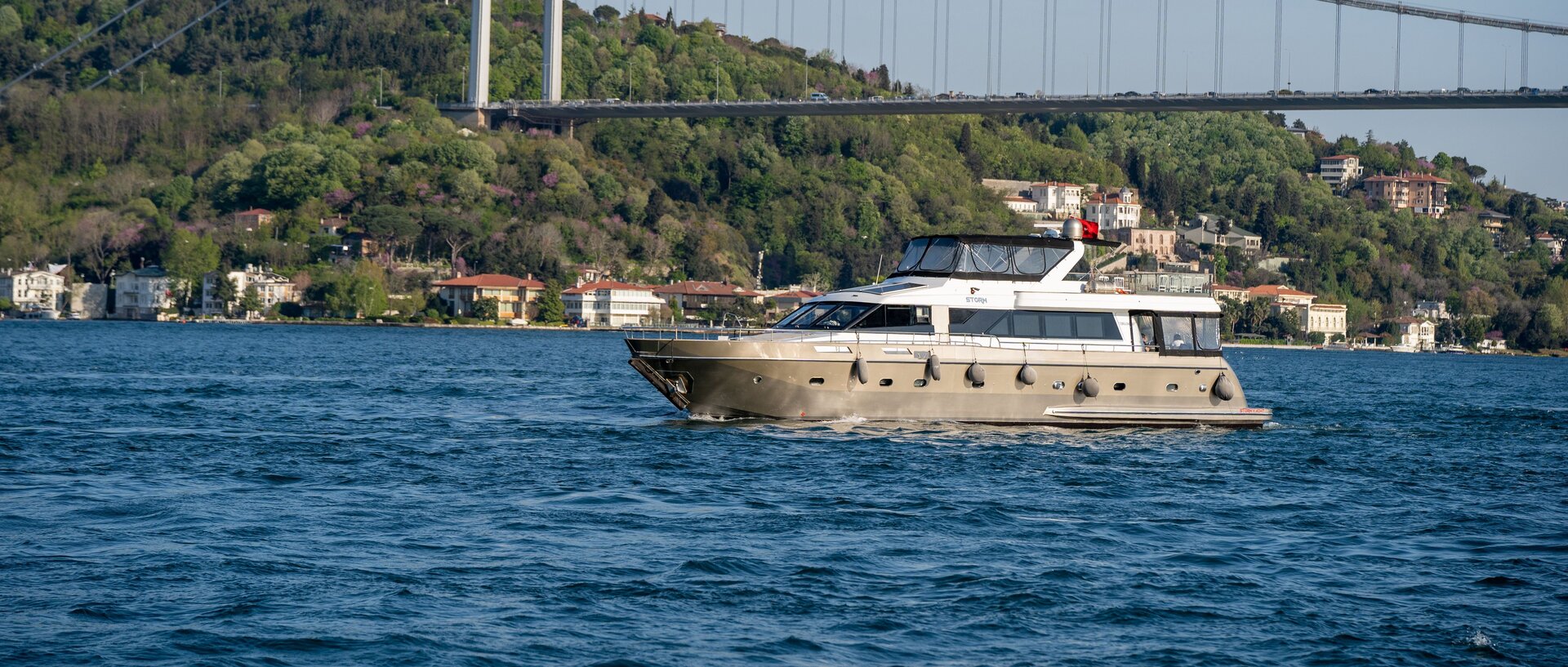 Eine luxuriöse Yacht fährt bei einer Istanbul Yacht Tour auf dem Bosporus unter der Fatih-Sultan-Mehmet-Brücke hindurch