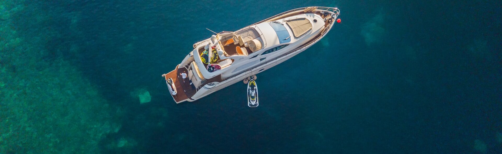 Eine Luxusyacht mit Wasserspielzeug ankert auf türkisblauem Wasser; ideal für eine exklusive Bootstour Mallorca