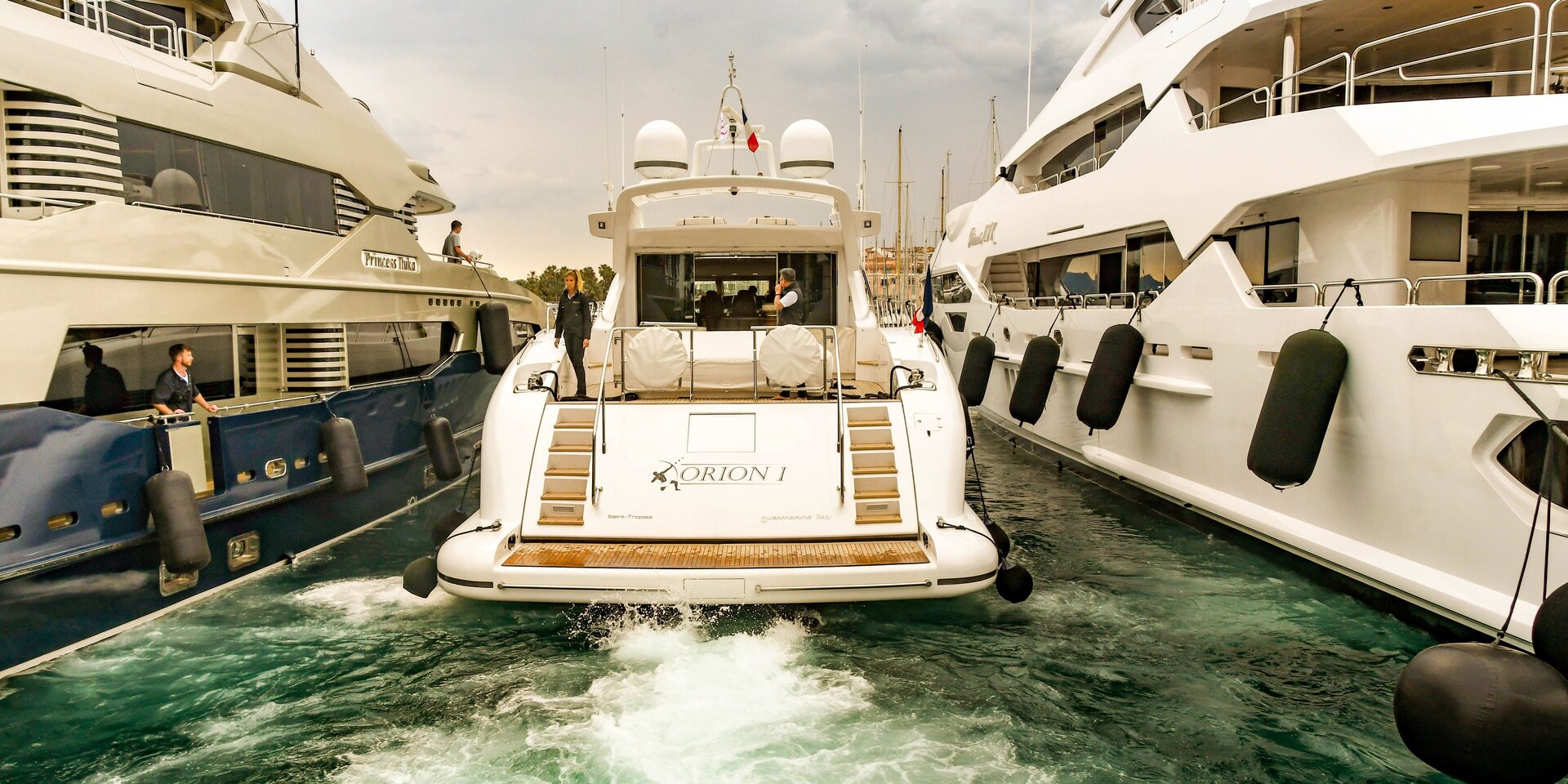 Eine weiße Motoryacht parkt mit aufgewühltem Kielwasser rückwärts im Hafen von Marmaris ein