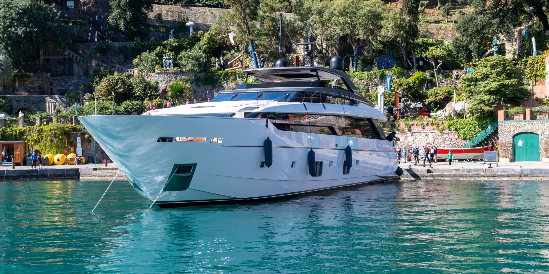 A sleek white luxury motor yacht docked near the lush coastline, perfect for a professional motor yacht rental Portonovi