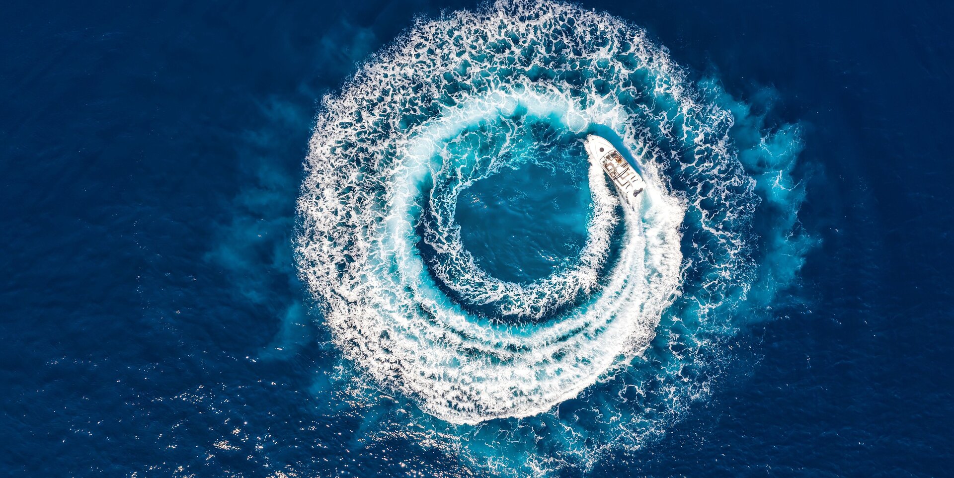 A fast boat creates a white wake circle during a Motor Yacht Charter Turkey in the Mediterranean