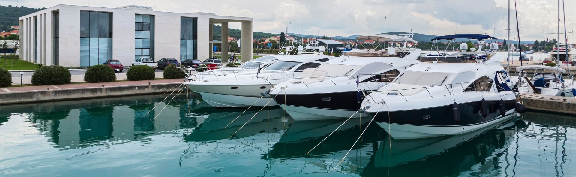 Moderne Motoryachten liegen im Yachthafen von Sukosan, Kroatien, direkt vor einem eleganten Gebäude