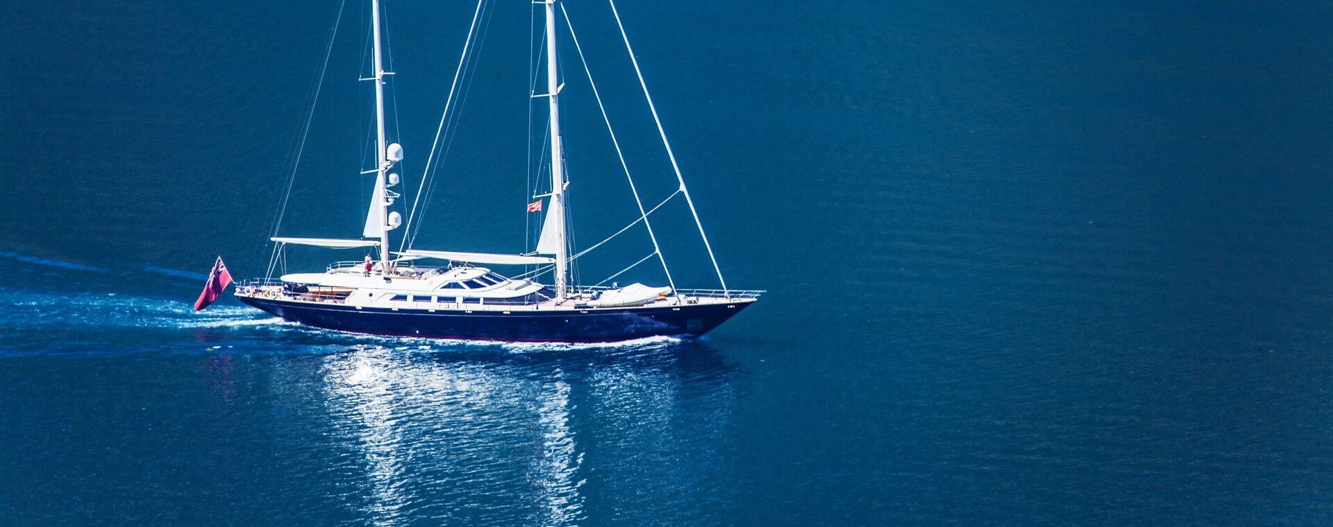 Eine luxuriöse Segelyacht fährt entlang der bergigen Küste bei einer Luxus Segelyacht in Bodrum