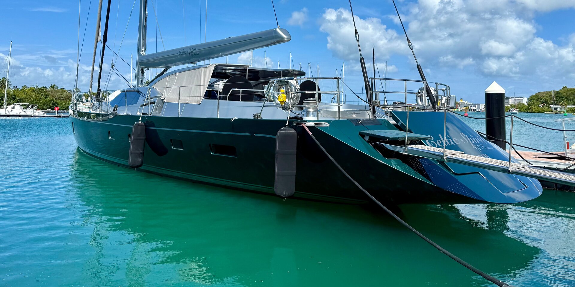 Вид с кормы на элитную парусную яхту, ошвартованную у причала и готовую к парусному отдыху с шкипером