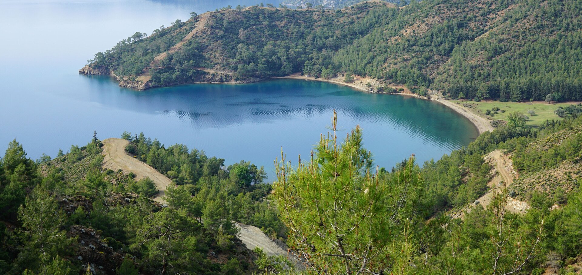 Scenic view of a secluded wooded bay for bareboat sailing in Göcek with calm blue waters