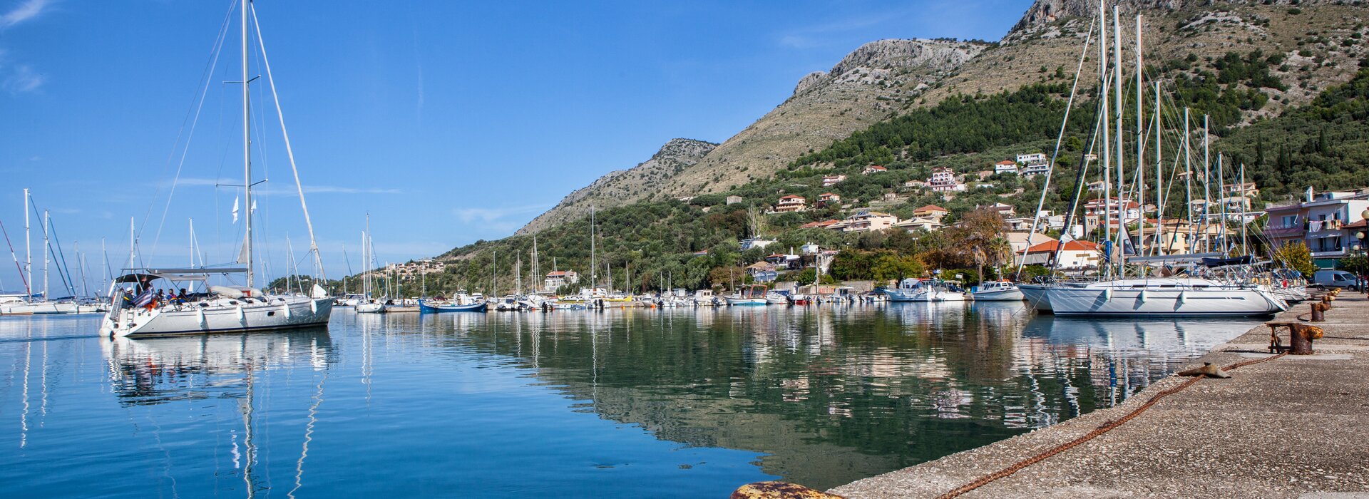 Moderne Segelyacht Charter Preveza beim Auslaufen aus dem Hafen vor malerischer Bergkulisse im Ionischen Meer