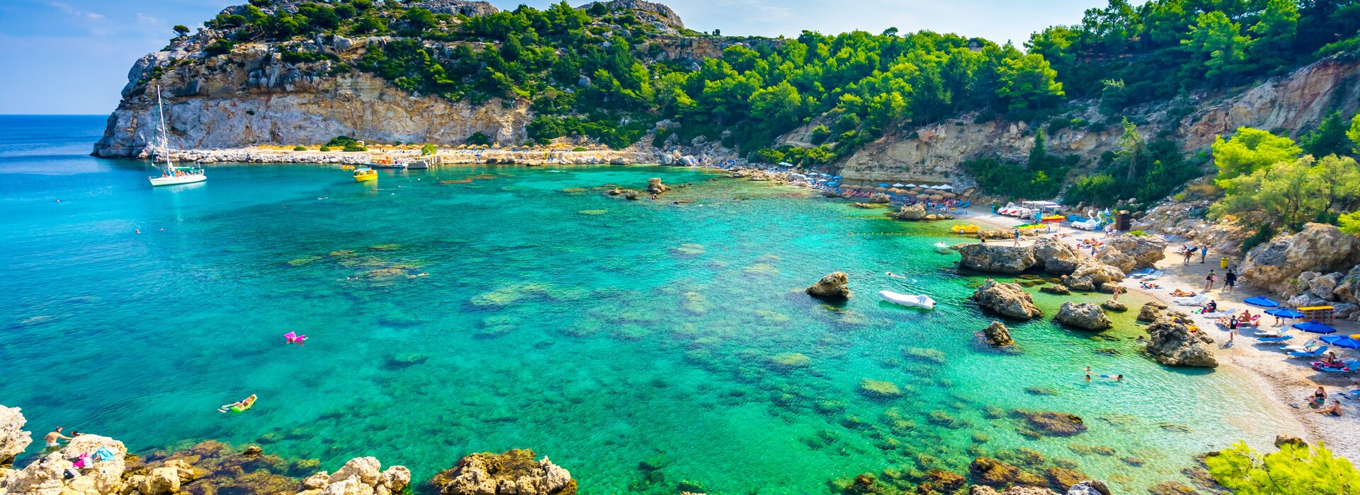 Ein weißes Segelboot in der Anthony Quinn Bay, der ideale Ort, um ein Segelboot mieten Rhodos Abenteuer zu erleben