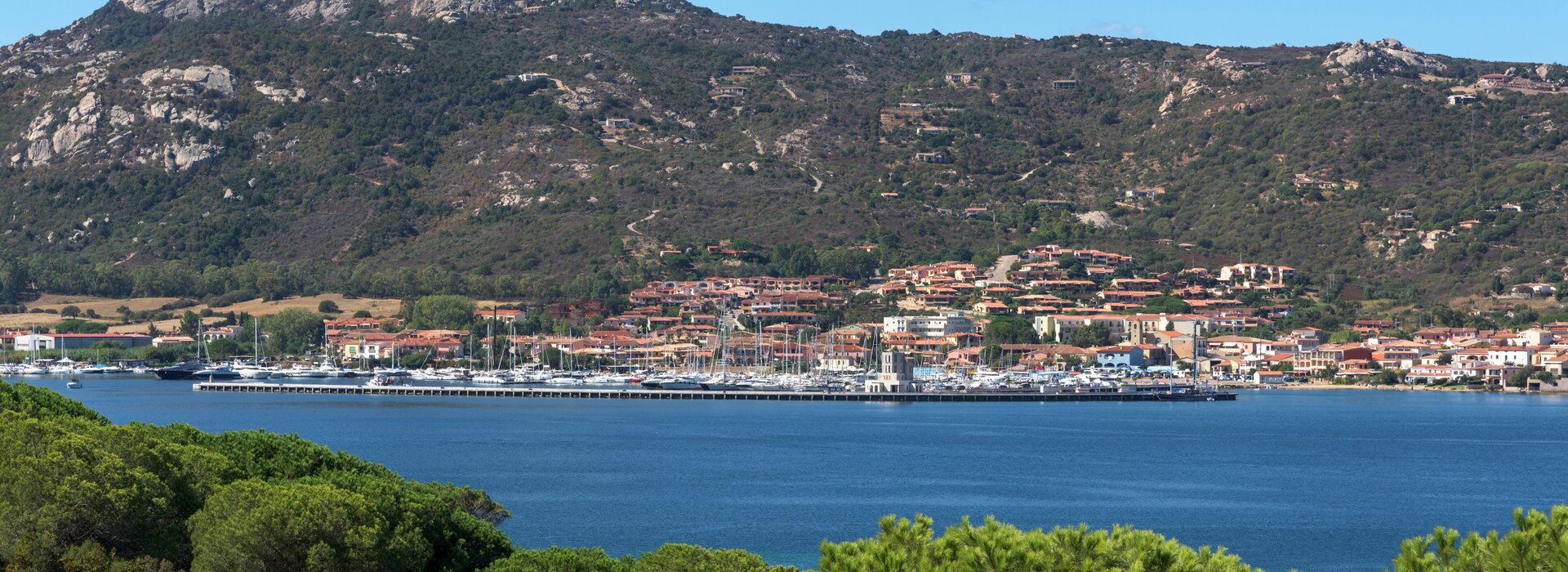 Панорама гавани Канниджоне на фоне зеленых холмов, лучший старт для чартера яхт в Канниджоне