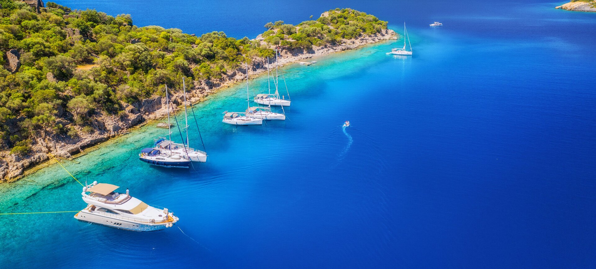 Luftaufnahme einer einsamen Bucht mit ankernenden Yachten beim Yachtcharter Göcek in kristallklarem Wasser
