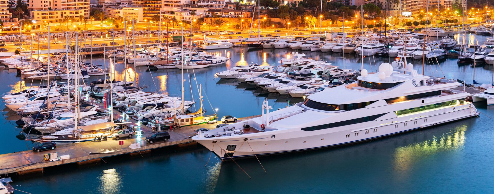 Beleuchteter Hafen von Palma bei Nacht mit einer luxuriösen Superyacht und der Option zum Boot mieten Mallorca