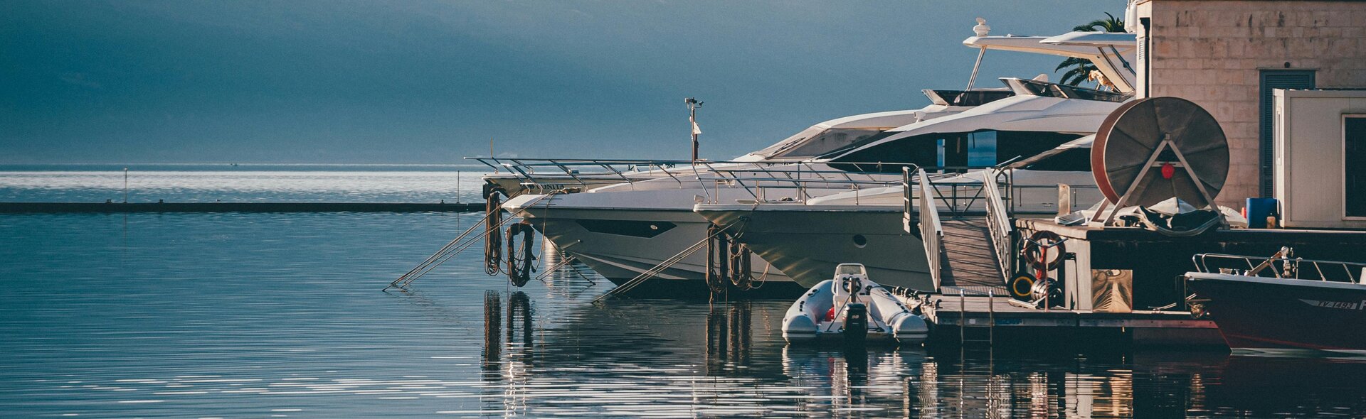 Несколько белых люксовых яхт ошвартованы у причала в порту, отличный выбор для элитного чартера яхт в Черногории