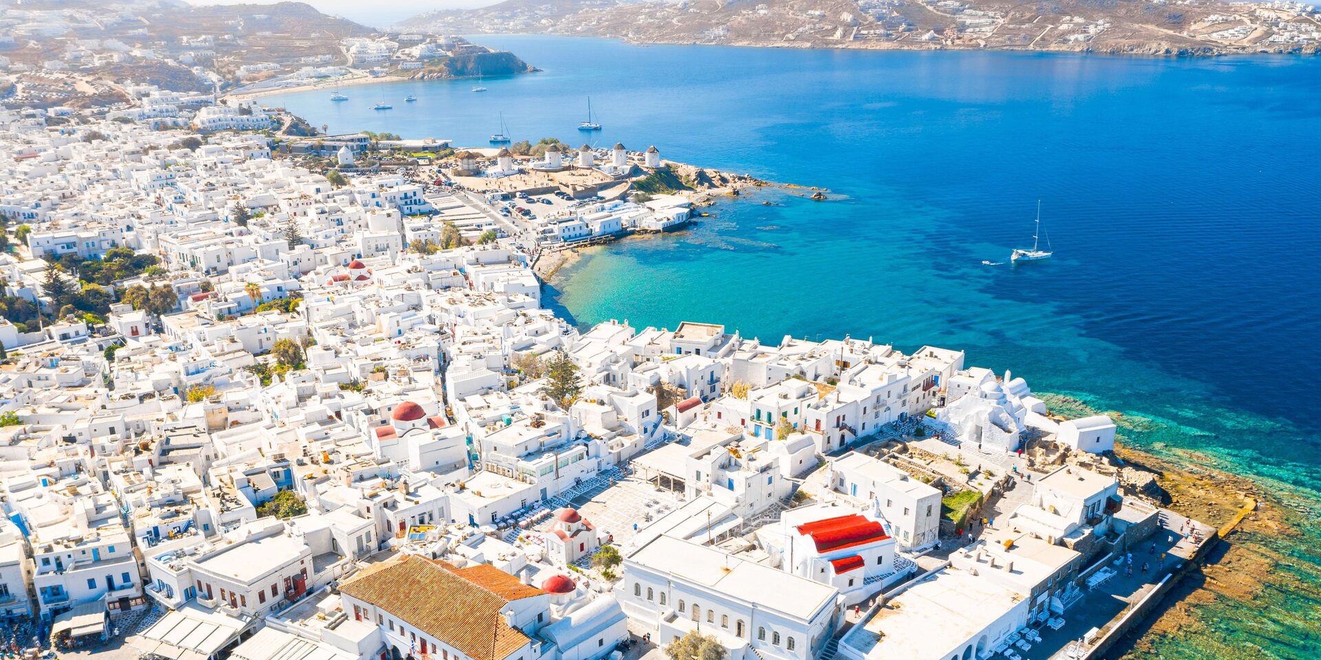 Panorama von Mykonos-Stadt mit weißen Häusern und tiefblauem Meer, der exklusive Ort, um eine Mykonos Yacht zu mieten