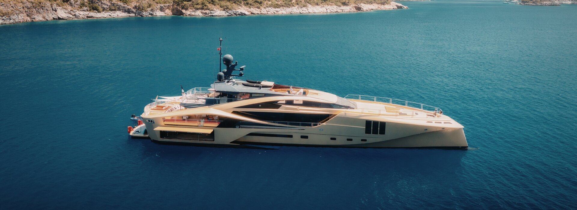 Kıyı açıklarında demirli altın sarısı süper yat; Portonovi lüks yat kiralama için ideal