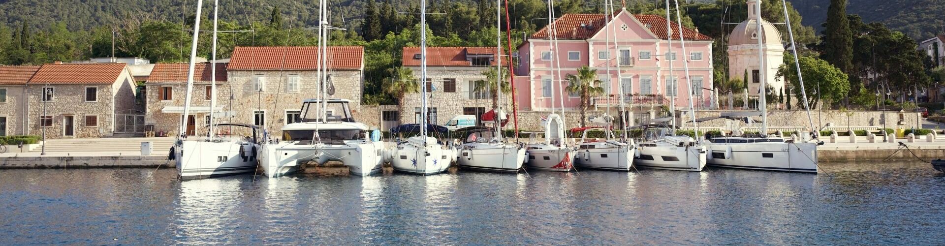 Yelkenliler ve katamaran, tarihi Hırvat evlerinin önündeki marinada bağlı